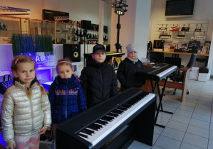 Dzieci stoją przy instrumentach w sklepie muzycznym